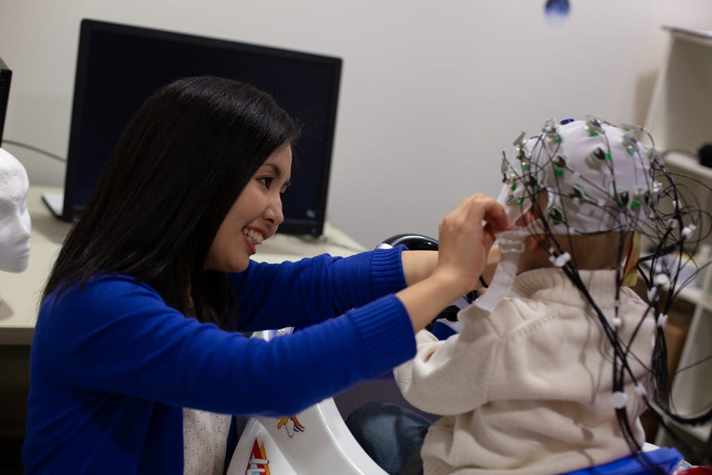 Psychology faculty Sawa Senzaki fitting subject with EEG cap