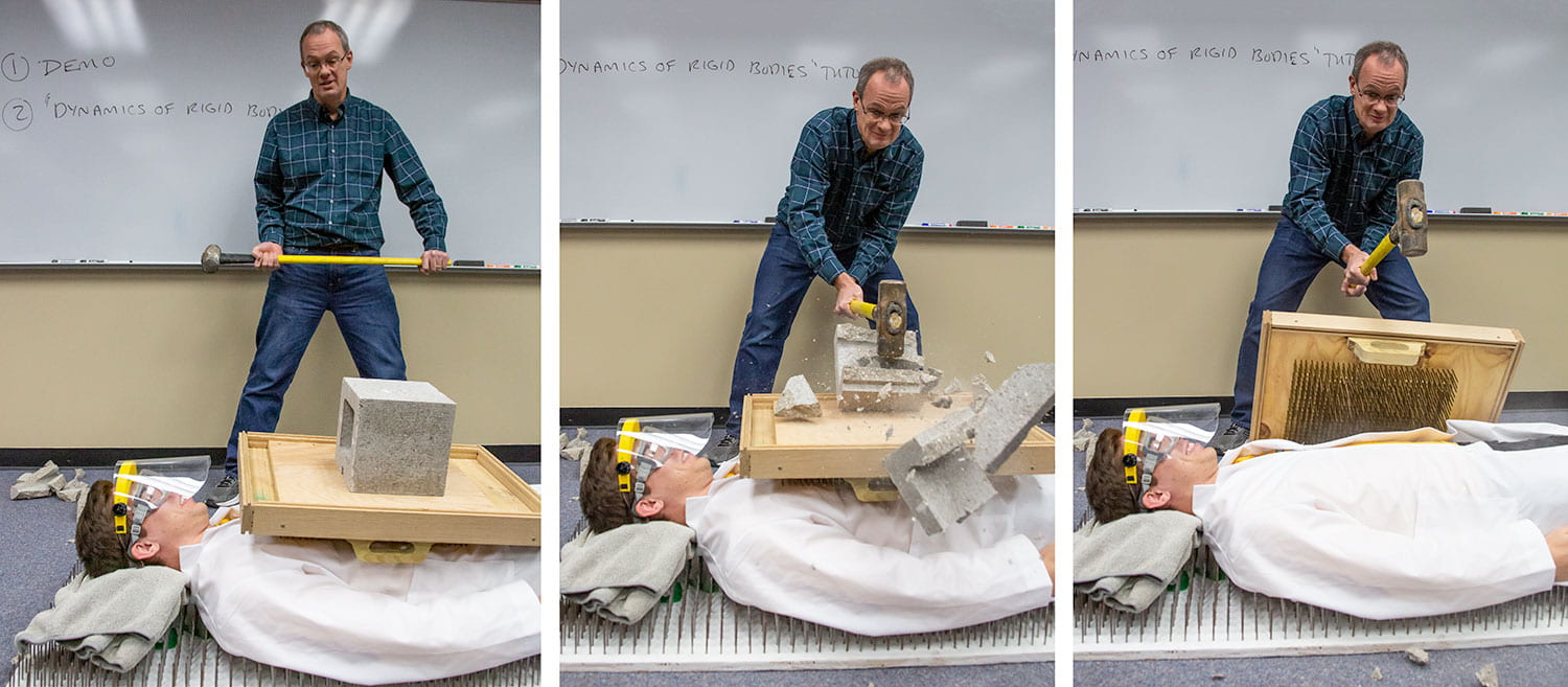 Brian Welsch smashes a block with a sledgehammer on a student lying on a bed of nails.