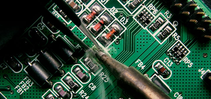 close up photo of instruments soldering an electrical board.