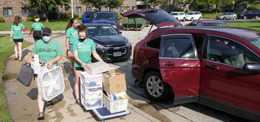 Photo of volunteer students loading a cart with boxes from a car to help an incoming new student move into the dorms outside Roy Downham Hall at the UW-Green Bay campus.