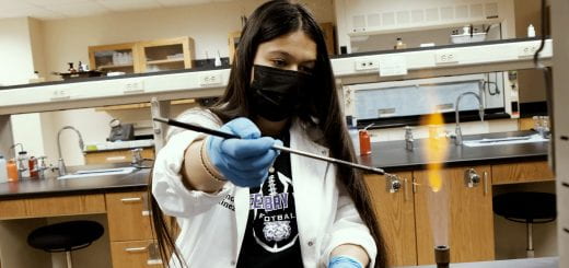 A Green Bay West High School’s Serious About Stem program student sterilizes a loop in the flame of a Bunsen burner inside the lab at UW-Green Bay during her Tiny Earth research.