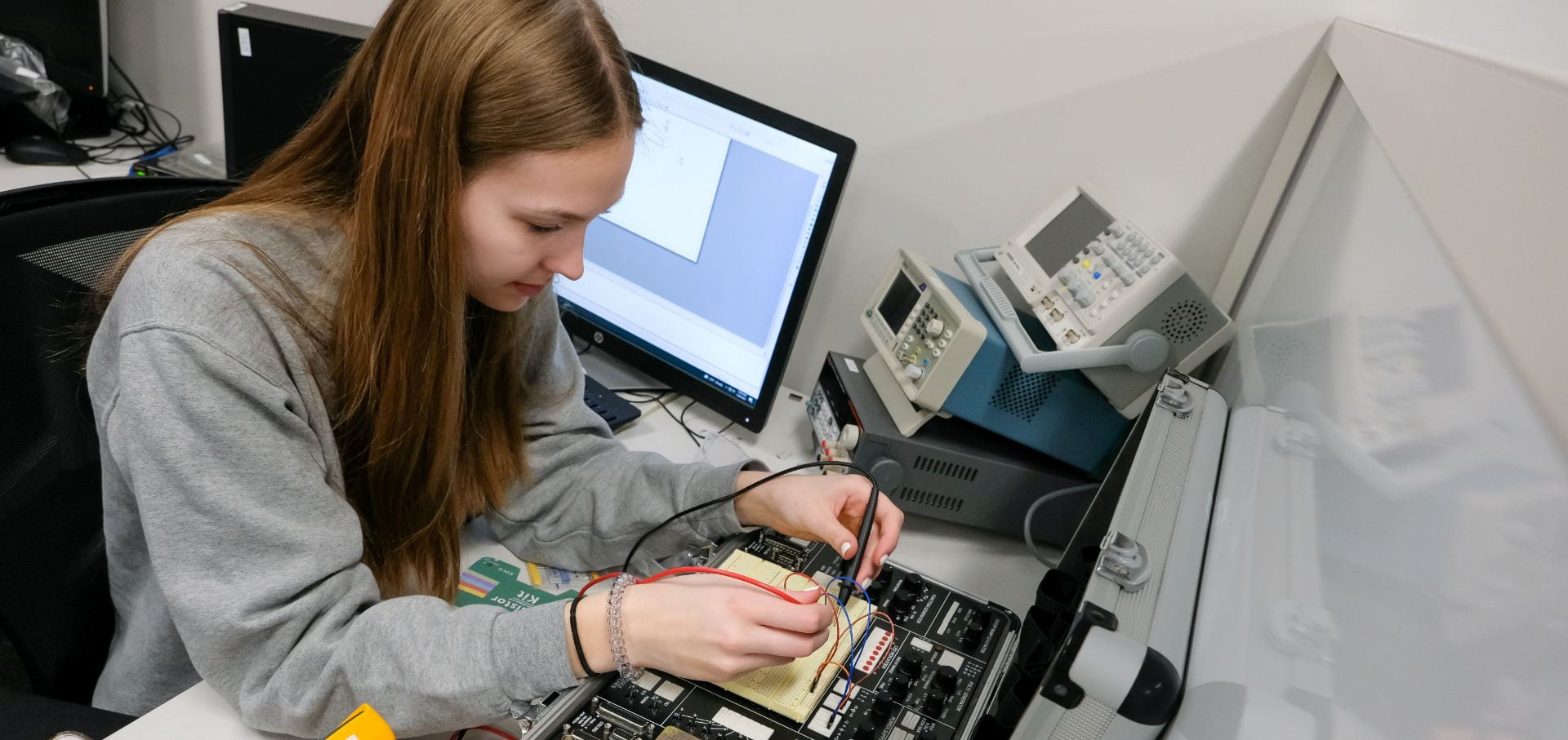 A female Electrical Engineering student uses a prototyping station to build and test circuits in Electrical Circuits I Lab at UW-Green Bay.