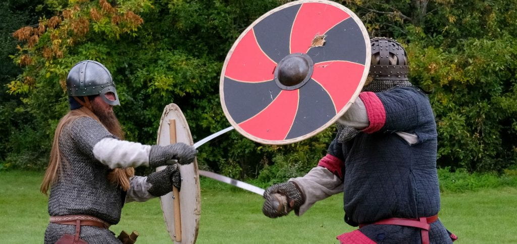 Two men dress in chainmail and steal helmets, use swords and shield to battle each other during the battle demonstrations at the Midwest Viking Festival.