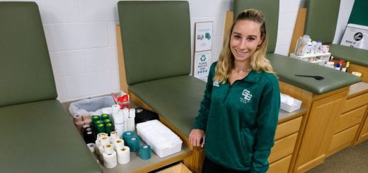 Madeleine Corbin, a student in the Master in Athletic Training Program, stands next to a treatment bay with a drawer open showing ace bandages, tape and elastic wrap, used to stablize athlete's joints. She is doing her clinical experience at the UW-Green Bay Sports Medicine Athletic Training Room at the Kress Center.